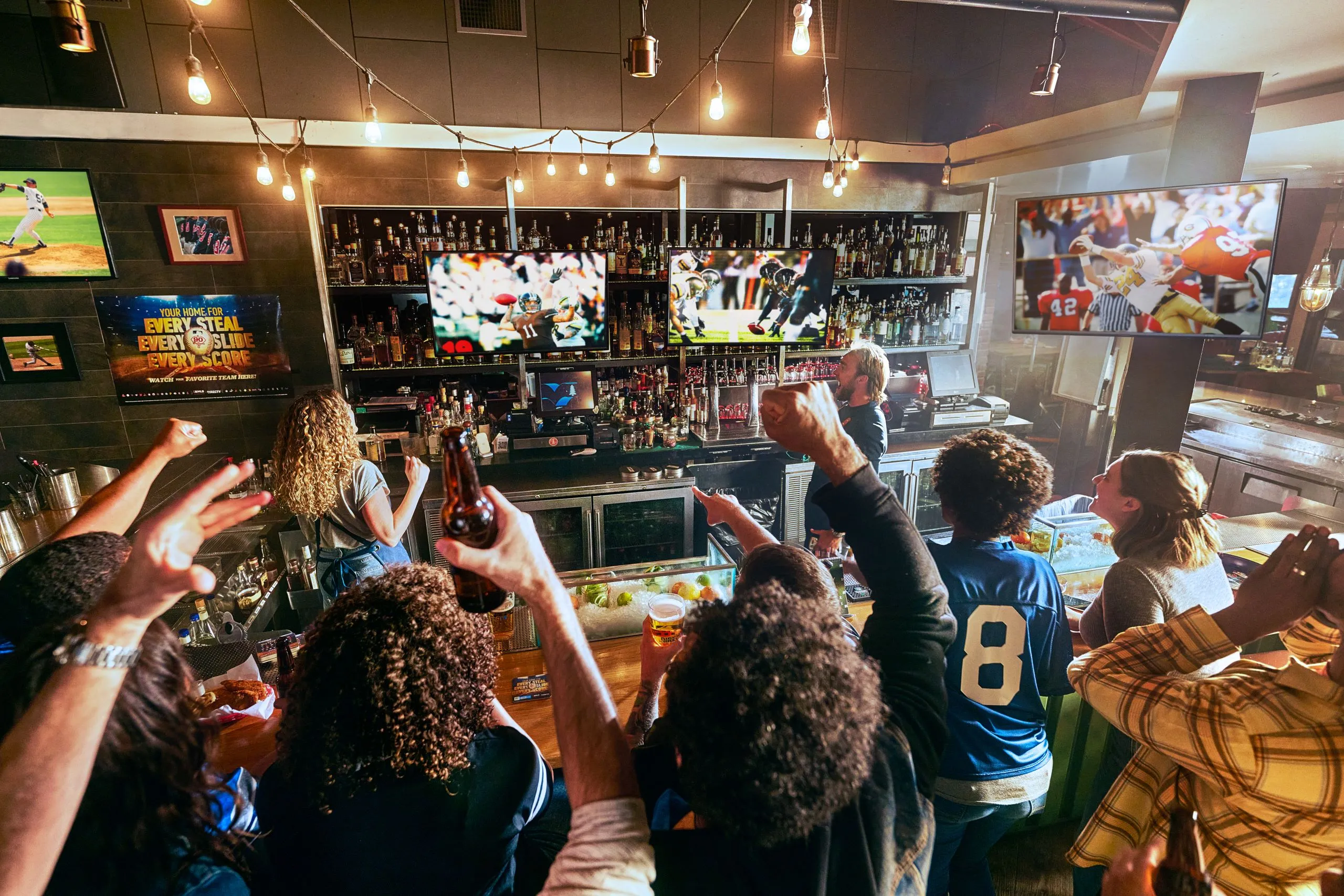 Fans cheering at a sports bar with games on every screen
